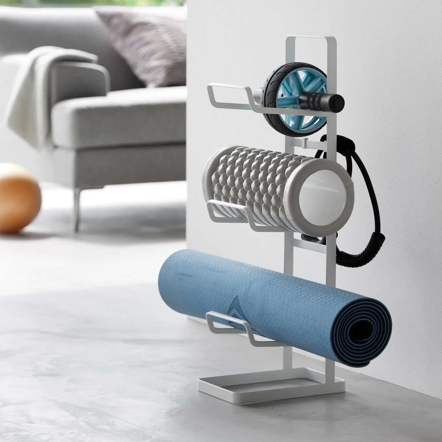 Yoga mat and roller set on a stand in a home setting