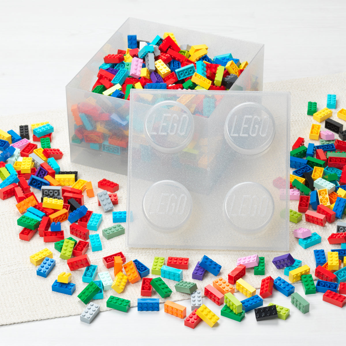 Colorful LEGO bricks with clear storage containers on a white background