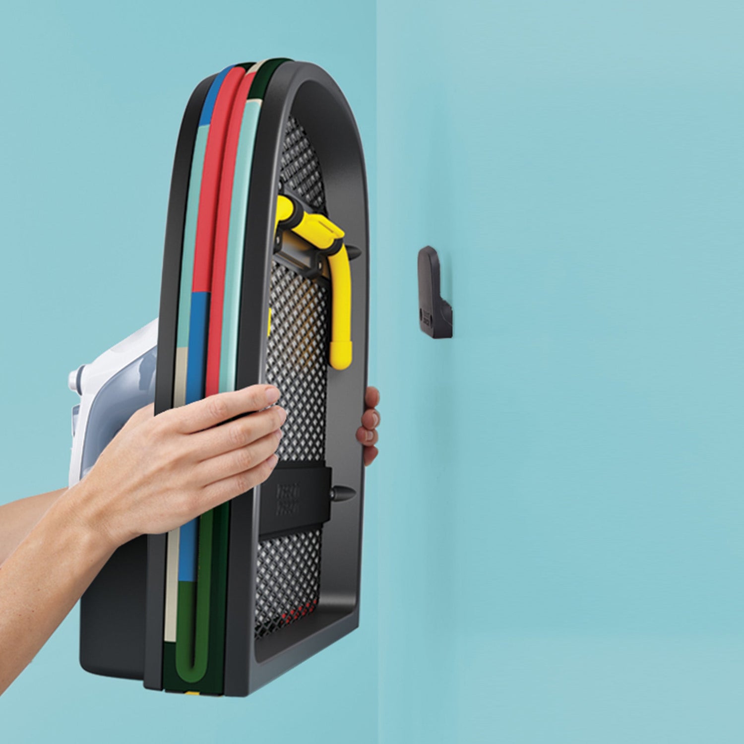 Person holding a vertical storage rack with colorful tools against a light blue background
