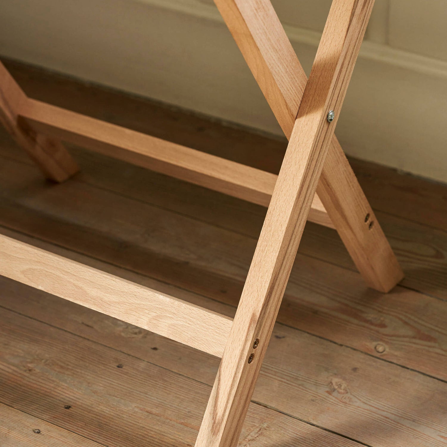 Wooden step ladder on a wooden floor with a neutral wall background