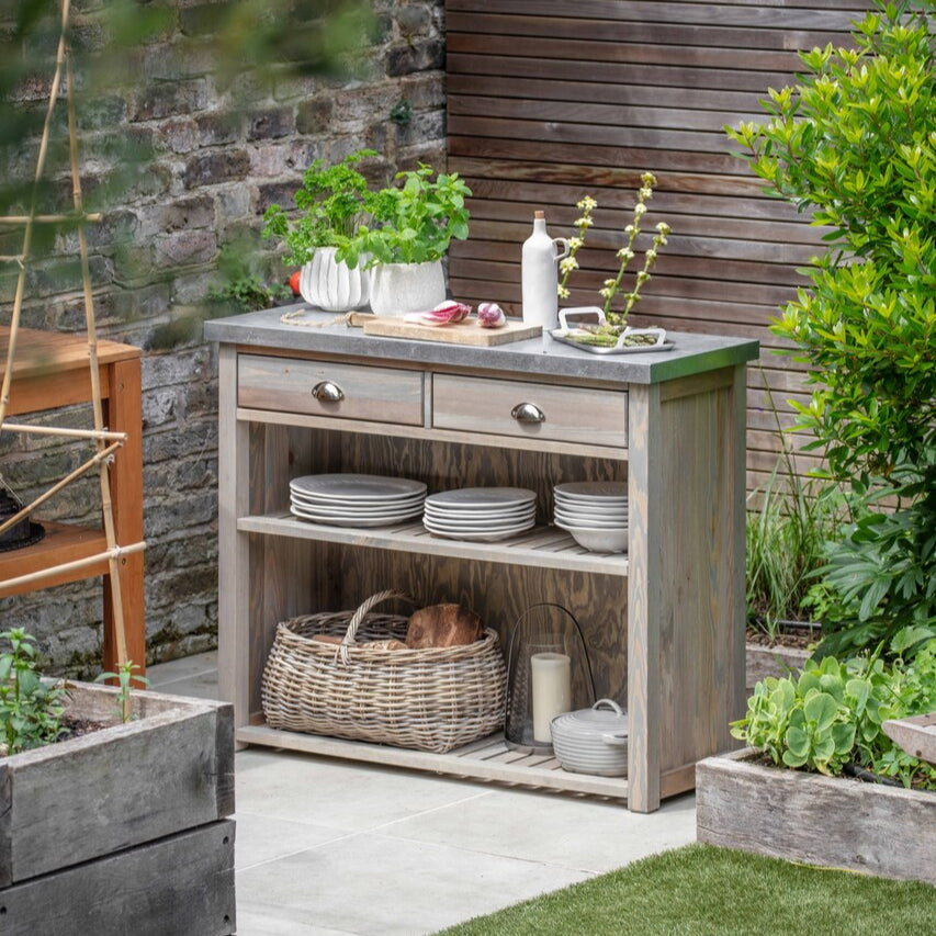 Outdoor setting with a wooden cabinet, plants, and a stone wall.