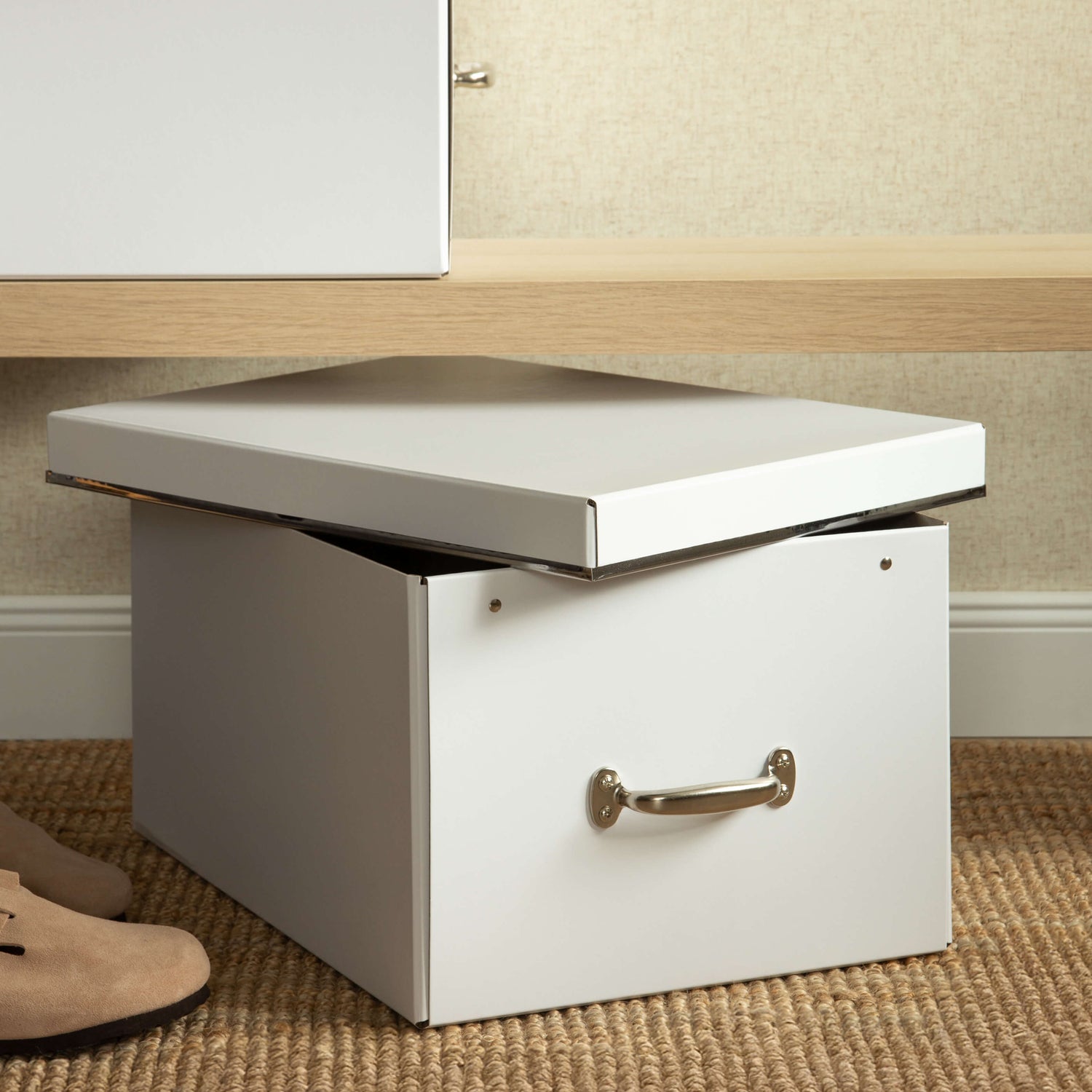 White storage box with a lid being lifted on a carpeted floor.