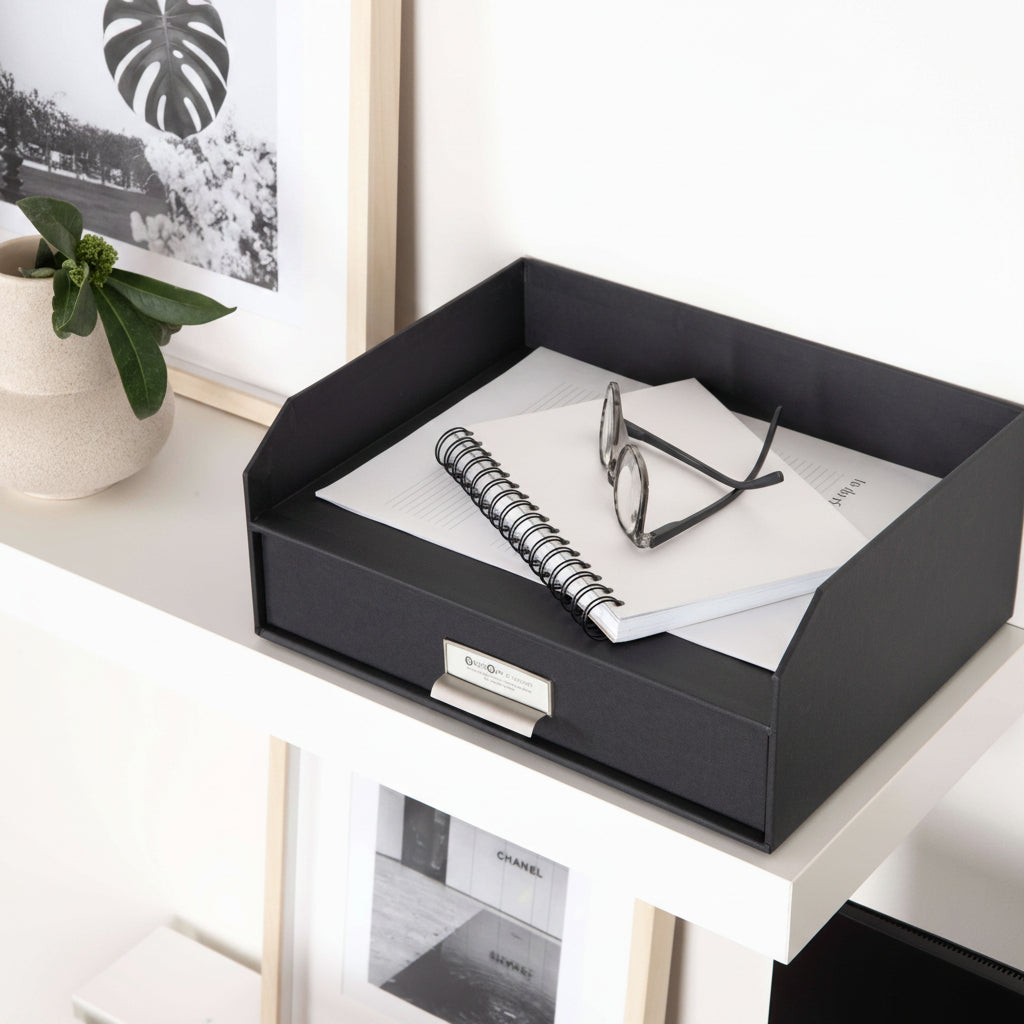 Black desk organizer with papers and glasses on a white surface
