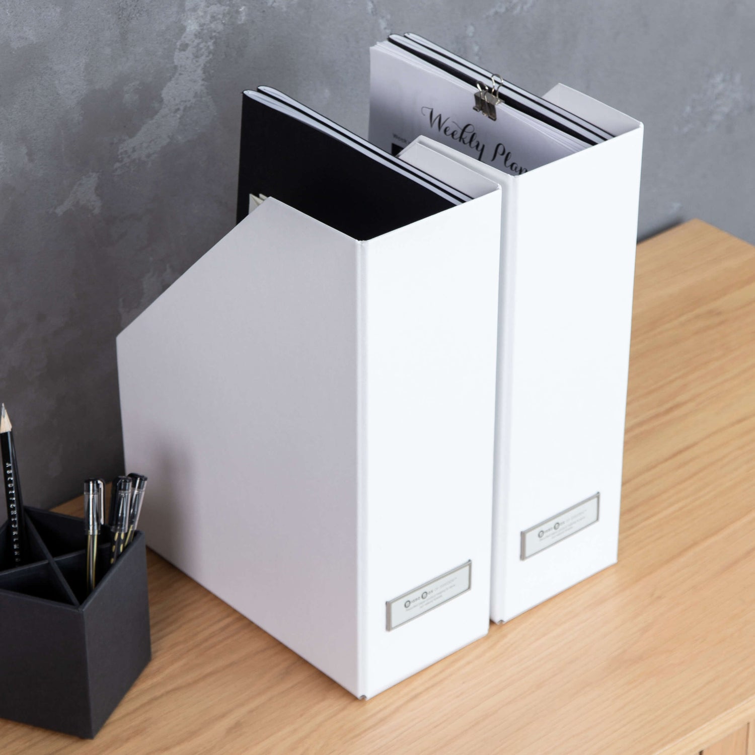 Two white binders on a wooden surface with a gray wall background