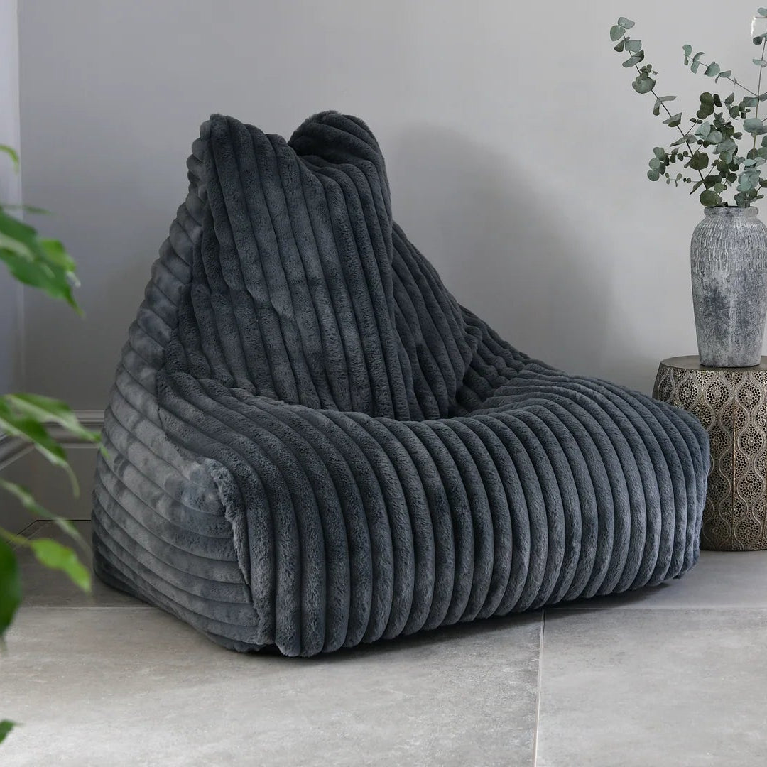 Gray bean bag chair in a room with a white table and decorative items.
