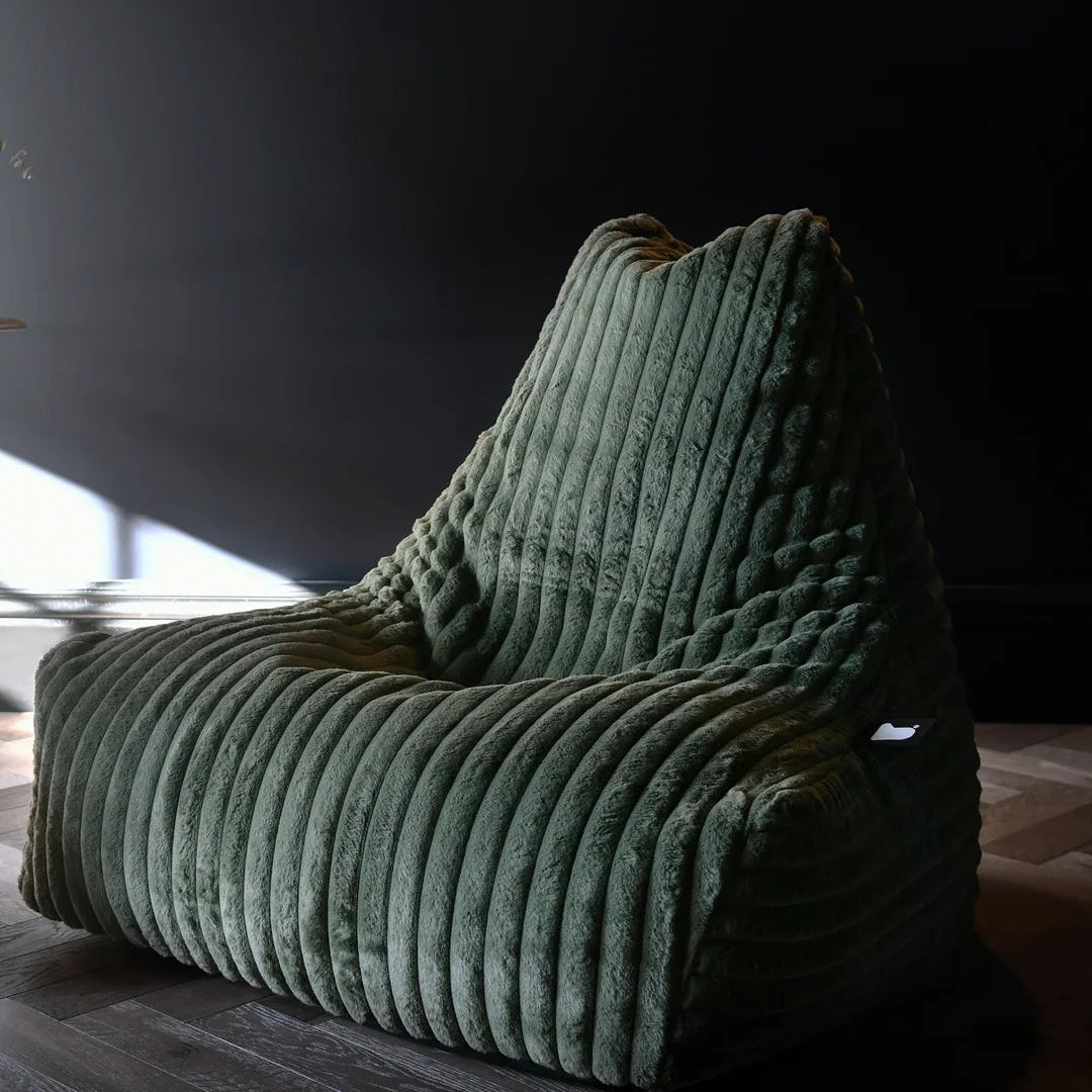 Green textured armchair in a room with a dark wall and light floor.