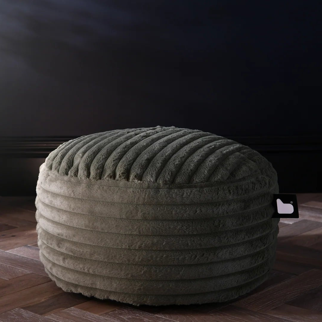 Textured ottoman on a wooden floor with a decorative vase in the background