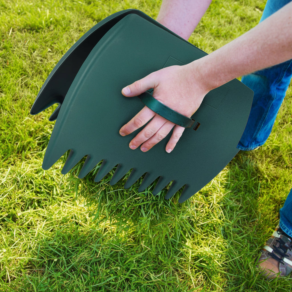 Person using a green leaf scoop to collect leaves on grass