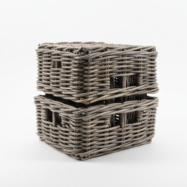 Two gray wicker baskets stacked on a light-colored floor with a tiled wall in the background.