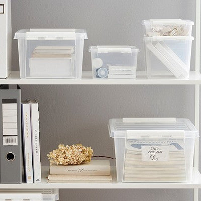 White shelving unit with storage boxes and binders against a gray wall