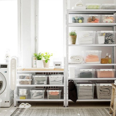 Laundry room with washing machine, shelves, and storage bins.
