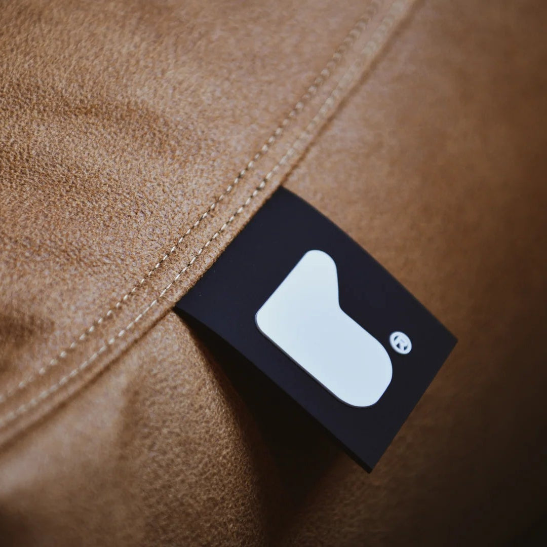 Close-up of a brown fabric surface with a black label featuring a white logo.