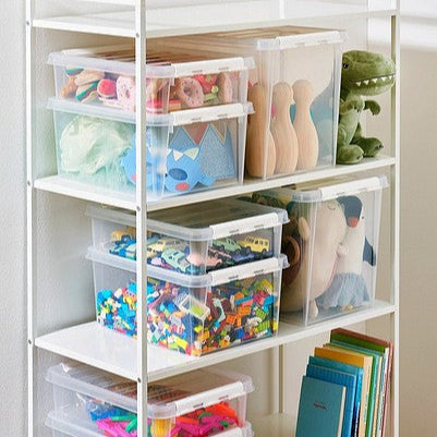 Storage rack with transparent storage bins containing toys and books on a white shelf.