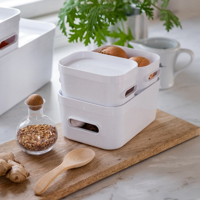 White kitchen organizer with eggs on a marble countertop with a plant in the background