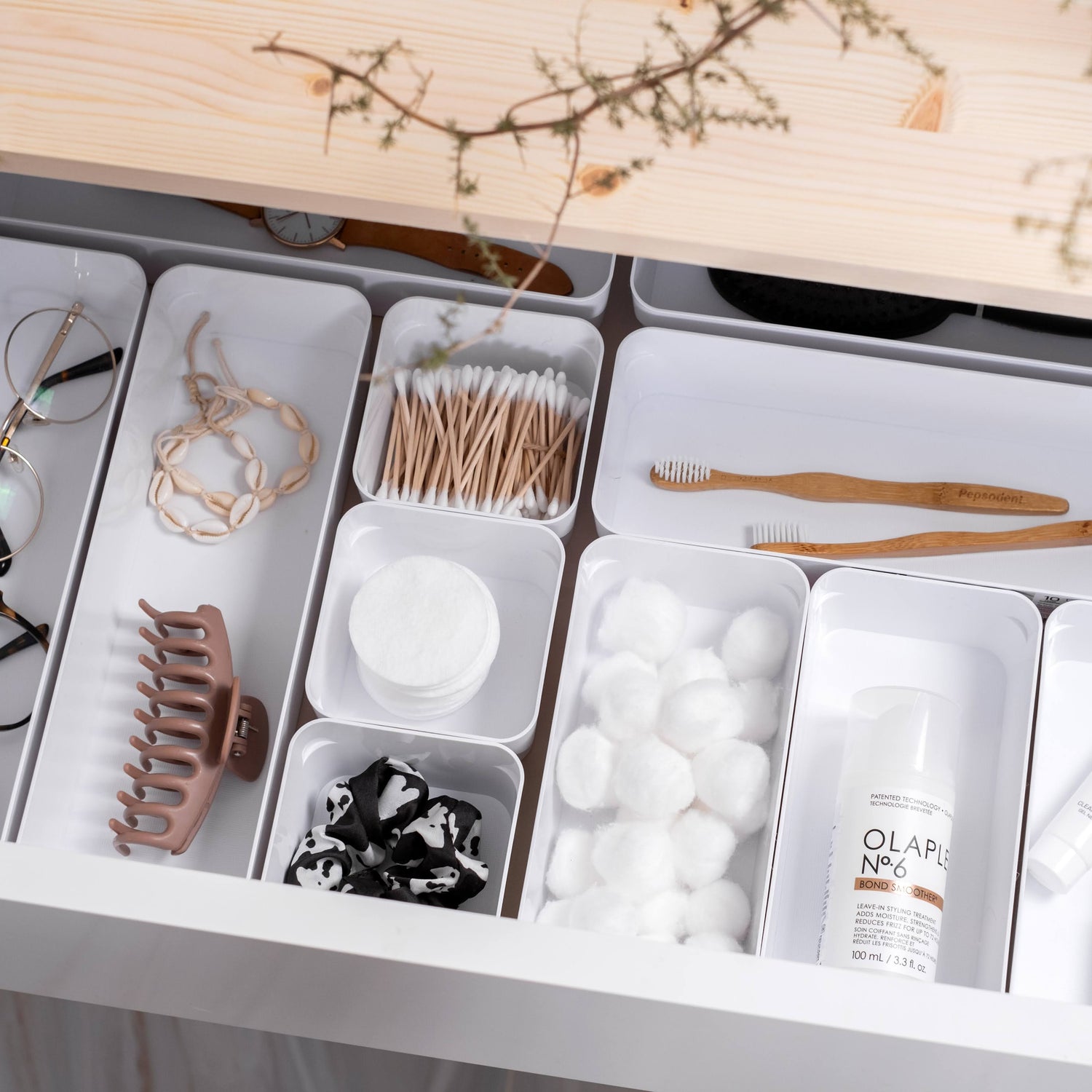 Organized drawer with various items including glasses, hair accessories, and skincare products.
