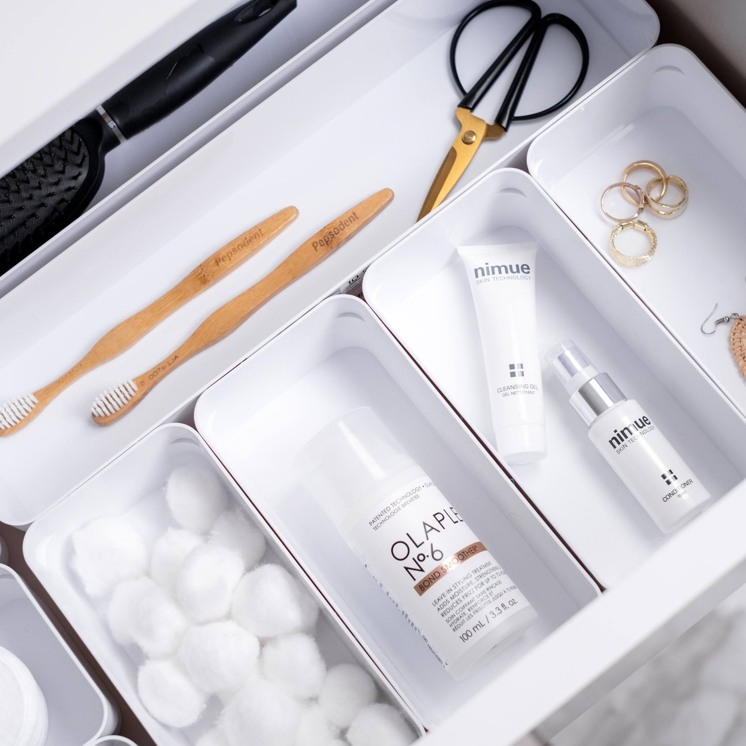 Organized drawer with personal care items including toothbrush, scissors, and skincare products.