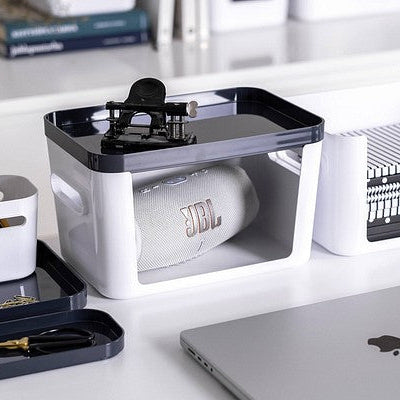 JBL speaker on a desk with office supplies and a laptop