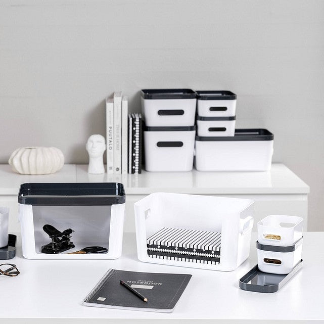 White desk with office supplies including books, containers, and stationery on a neutral background