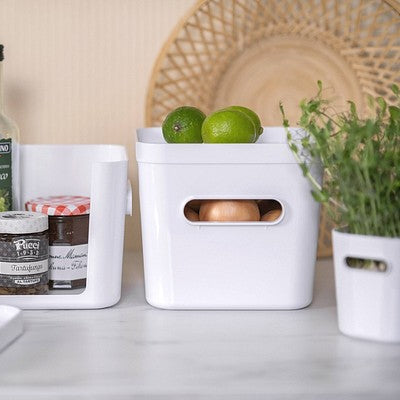 White kitchen storage bins with bottles and ingredients on a countertop