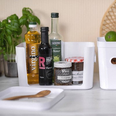 White kitchen storage bins with bottles and ingredients on a countertop