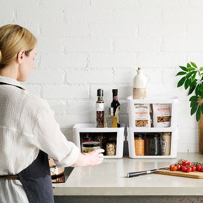 Person preparing food in a kitchen with various ingredients and utensils on a counter.
