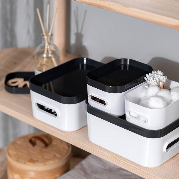 Set of black and white storage bins on a wooden shelf with decorative items.