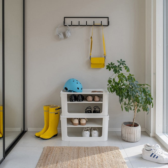 Room with storage shelves, yellow boots, and a helmet near a large window.