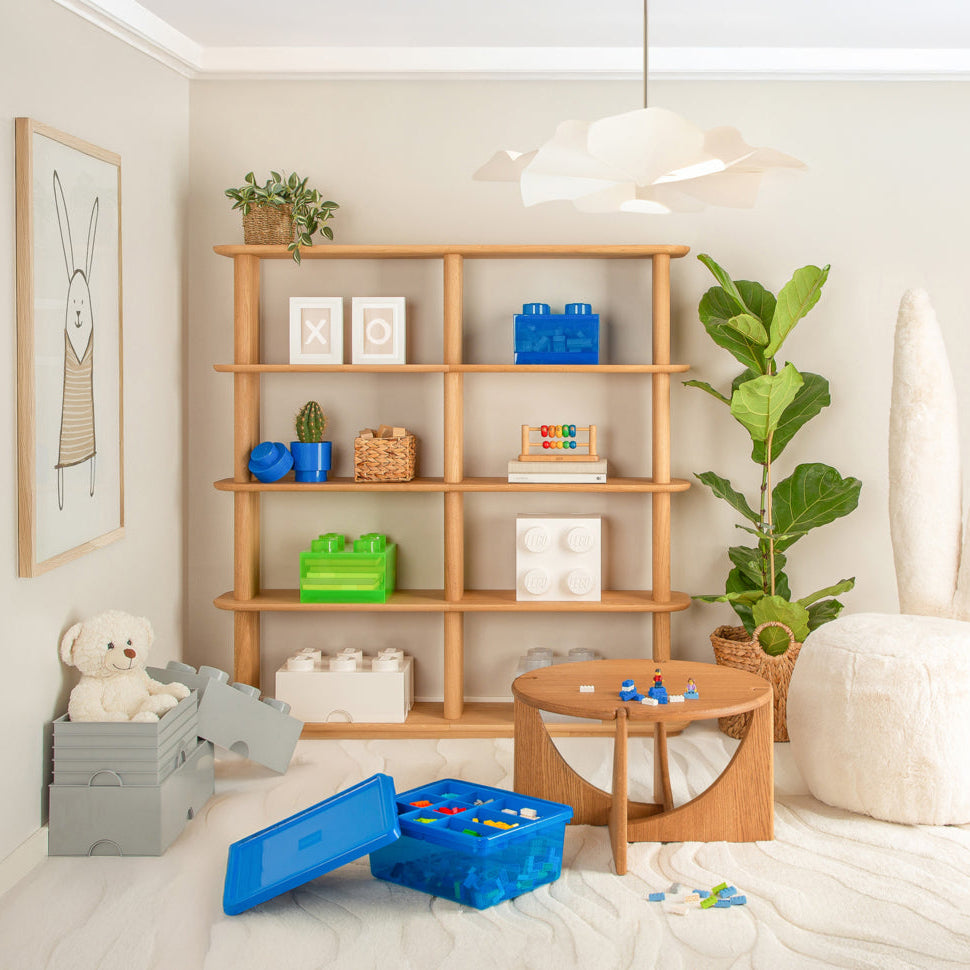 Children's playroom with wooden shelves, toys, and a white chair with bunny ears.