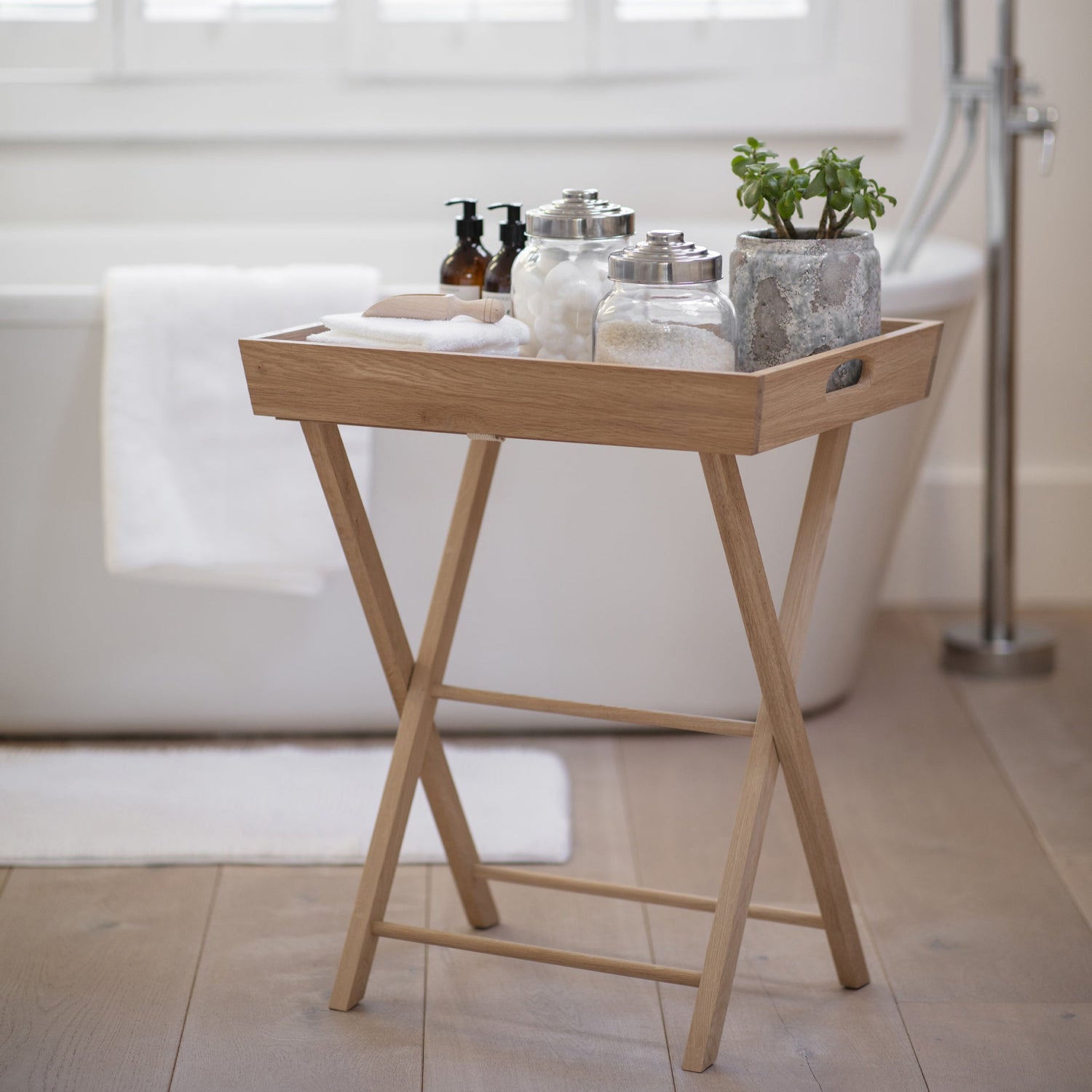 Wooden tray with bath items on a stand in a bathroom setting