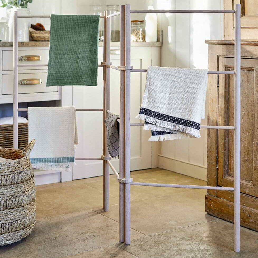 Towel rack with green, white, and patterned towels in a bathroom setting.