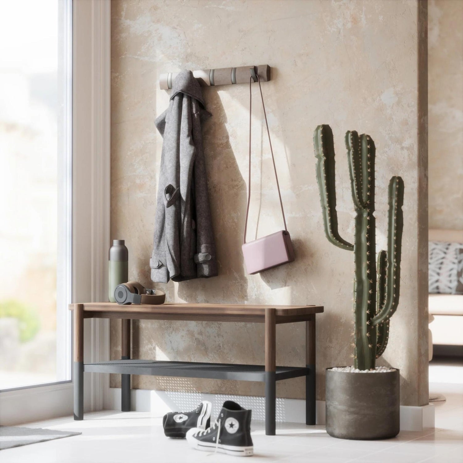 Entryway with wooden bench, cactus plant, and hanging clothes