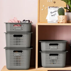 Stack of gray storage baskets labeled with various items on a wooden shelf.