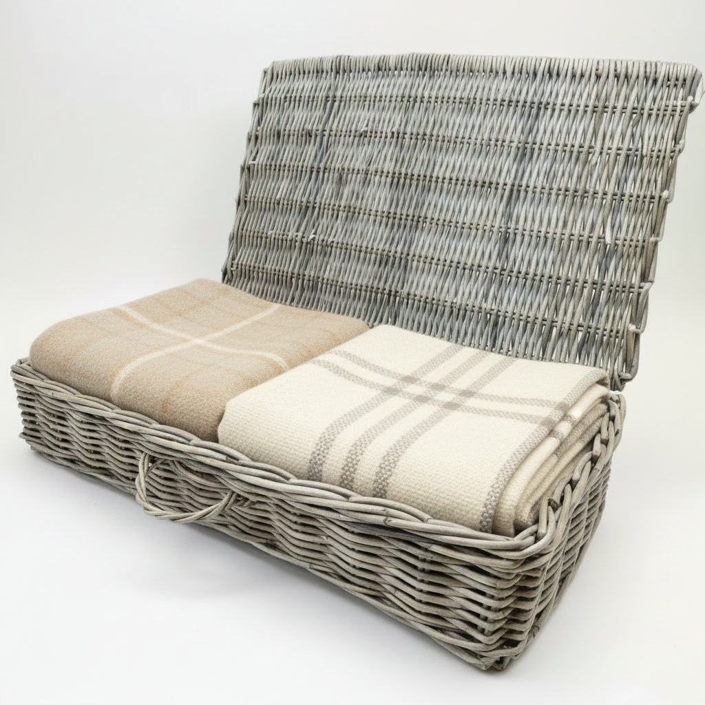 Wicker basket with blankets inside on a plain background
