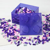 Purple LEGO brick container with scattered LEGO pieces on a white background