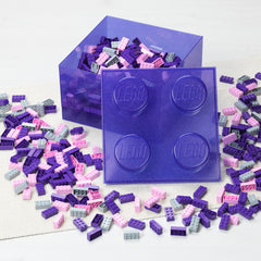Purple LEGO brick container with scattered LEGO pieces on a white background