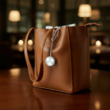 Black leather bag with a pearl decorative charm on a blurred background