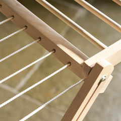 Close-up of a wooden hammock frame with ropes against a blurred natural background