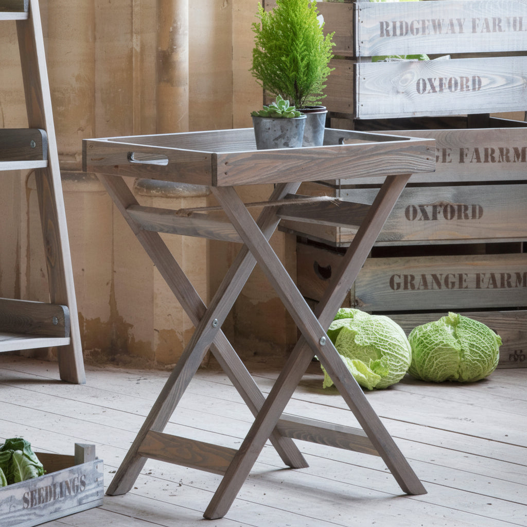 Wooden folding table with crates and plants in a rustic setting