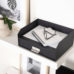 Black desk organizer with papers and glasses on a white surface