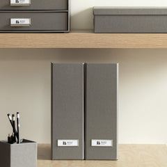 Gray office supplies including folders, a pen holder, and a notepad on a wooden shelf.