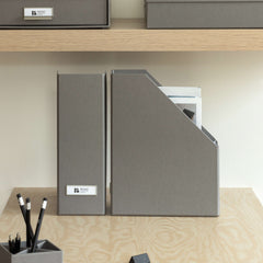 Gray office supplies including folders, a pen holder, and a notepad on a wooden desk.