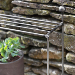 Metal plant stand with a potted plant against a stone wall