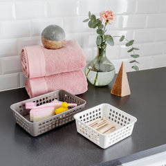 Baskets on a kitchen counter with a pink towel and decorative items.