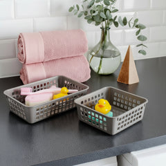 Baskets on a kitchen counter with a pink towel and decorative items.
