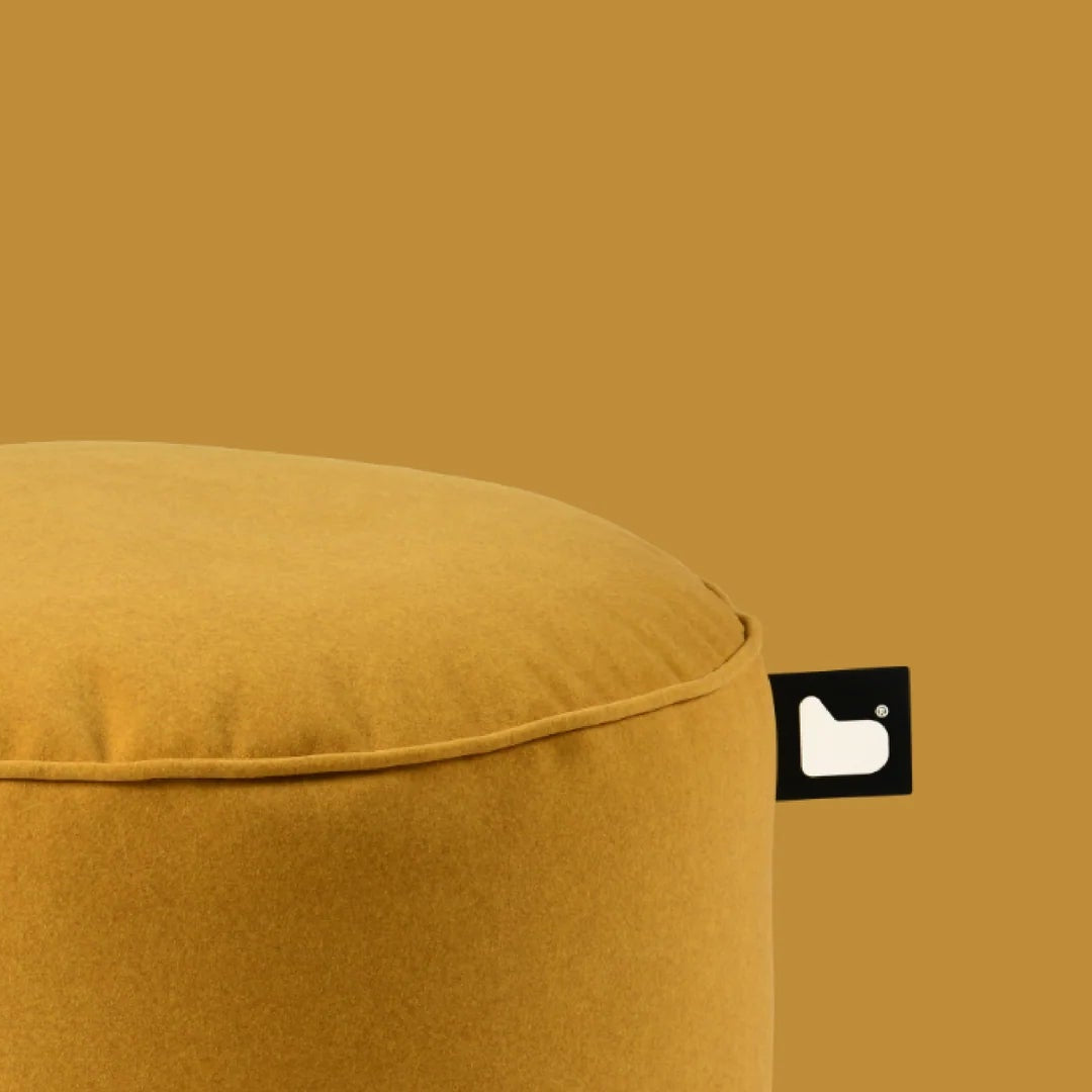 Mustard yellow ottoman with a brand logo on a matching background