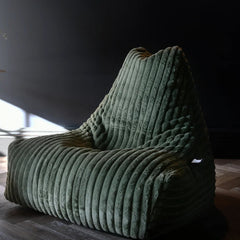 Green textured armchair in a room with a dark wall and light floor.