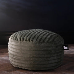 Textured ottoman on a wooden floor with a decorative vase in the background