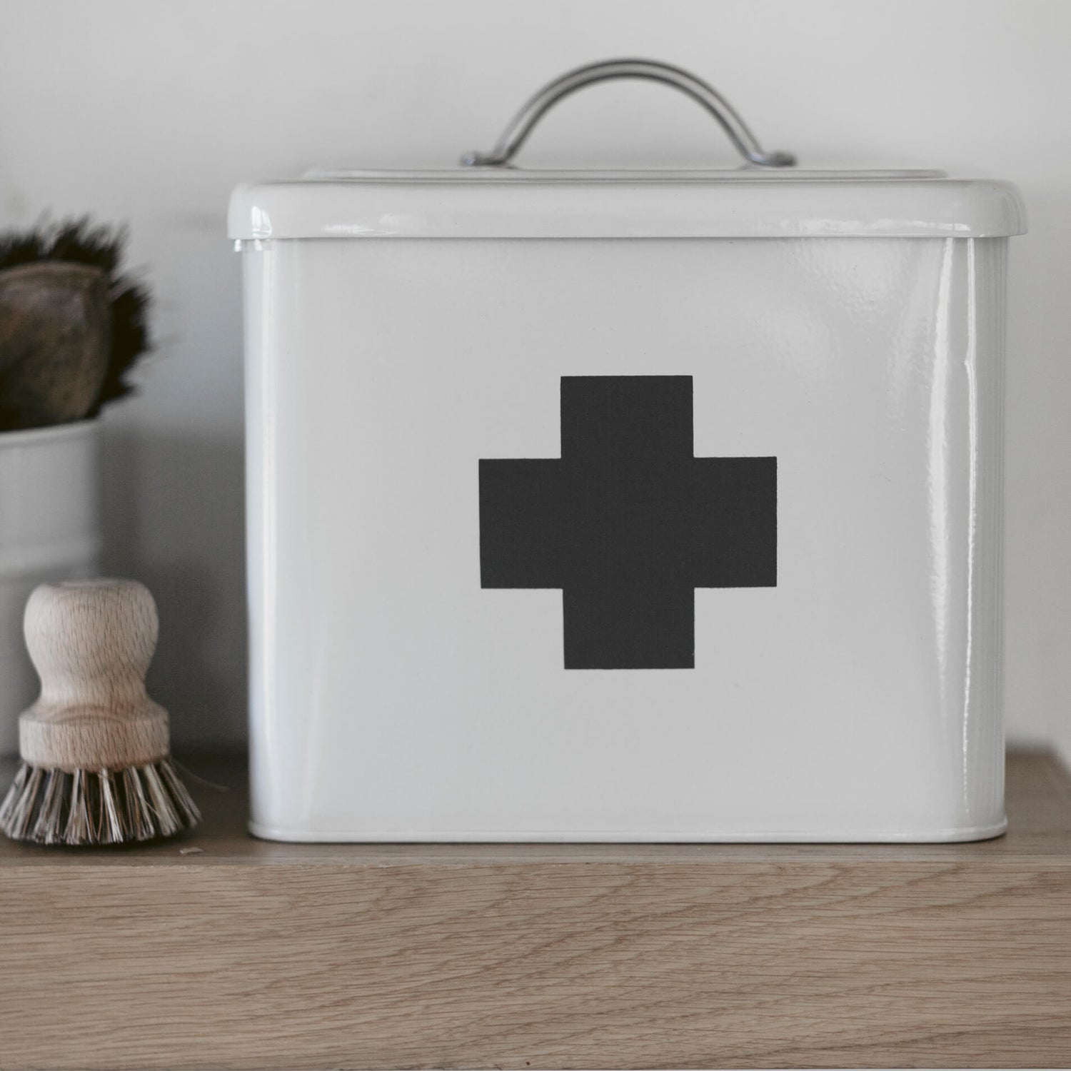 White storage container with a black cross on a wooden surface
