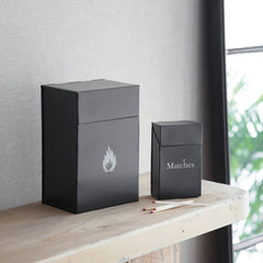 Two black matchboxes with 'Matches' text on a wooden surface.
