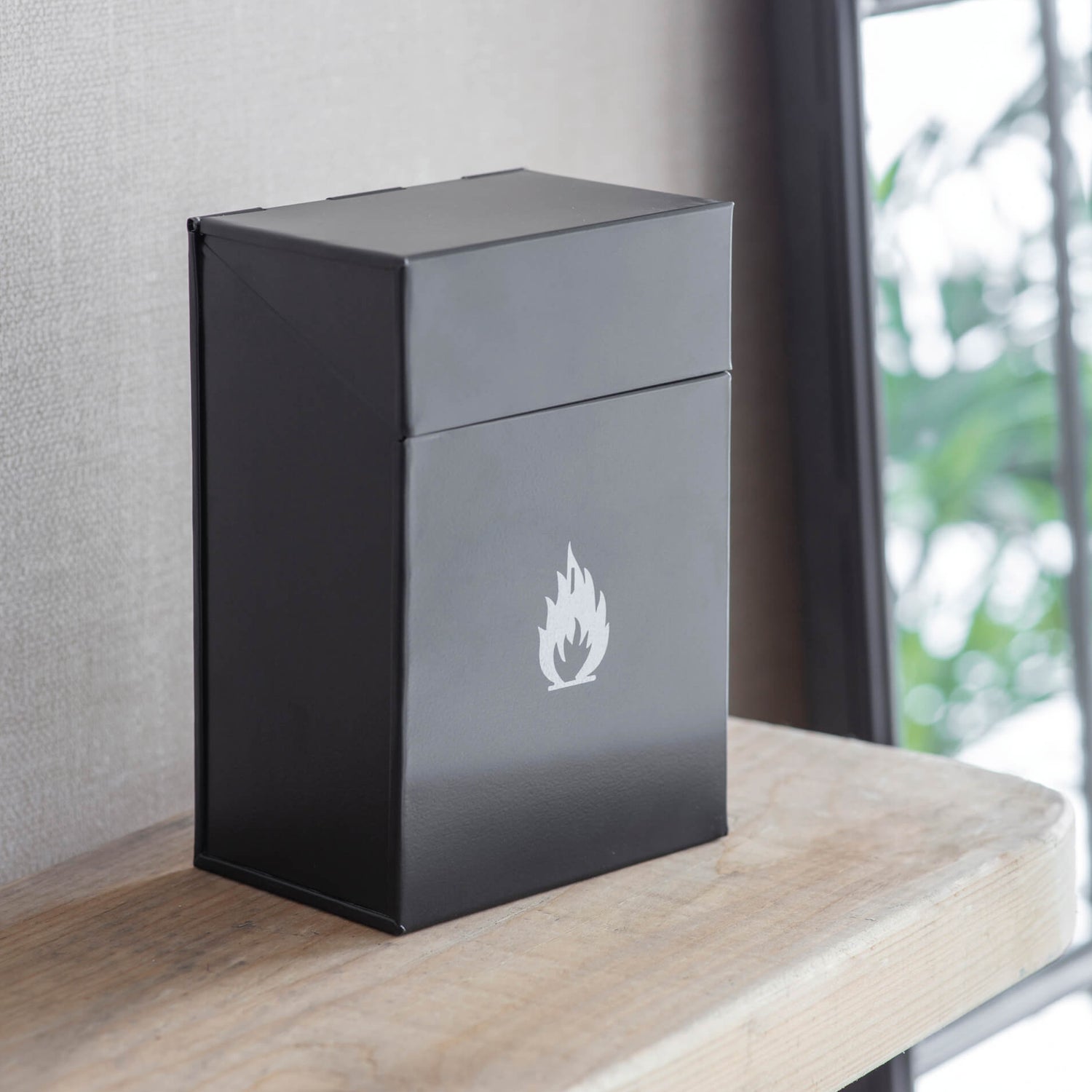 Black rectangular box with a white flame logo on a wooden surface.